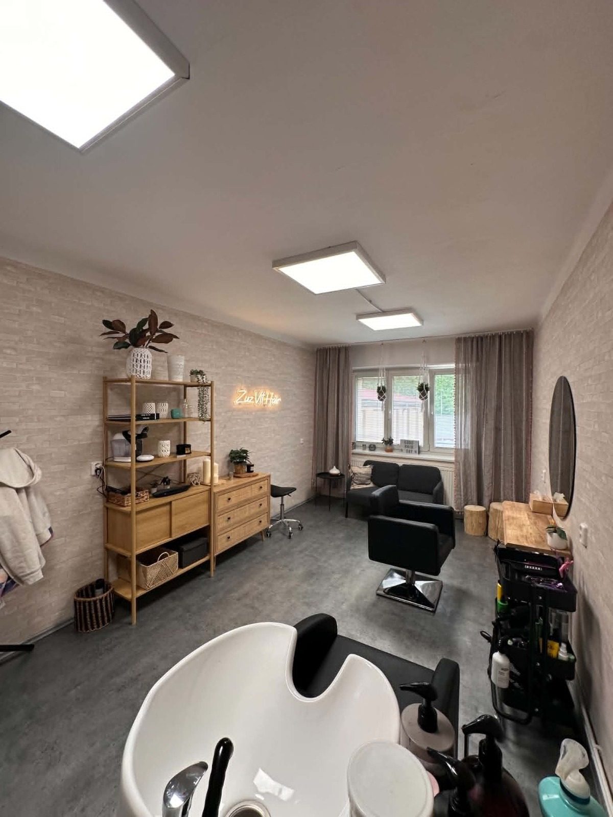 Interiér salonu Zuz Vit Hair — mycí box, kadeřnické křeslo a neonový nápis na cihlové zdi